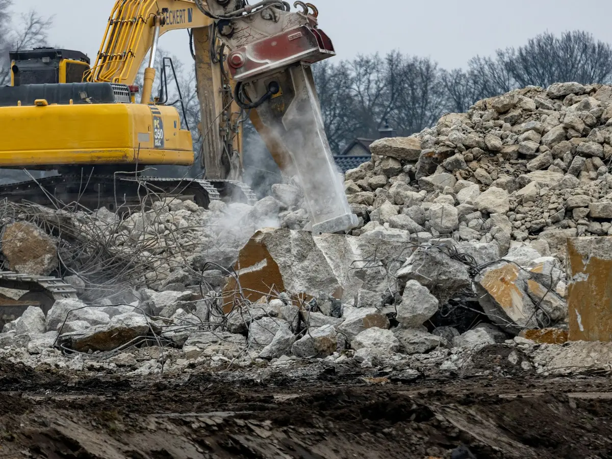 Excavator breaker demolishing a concrete slab