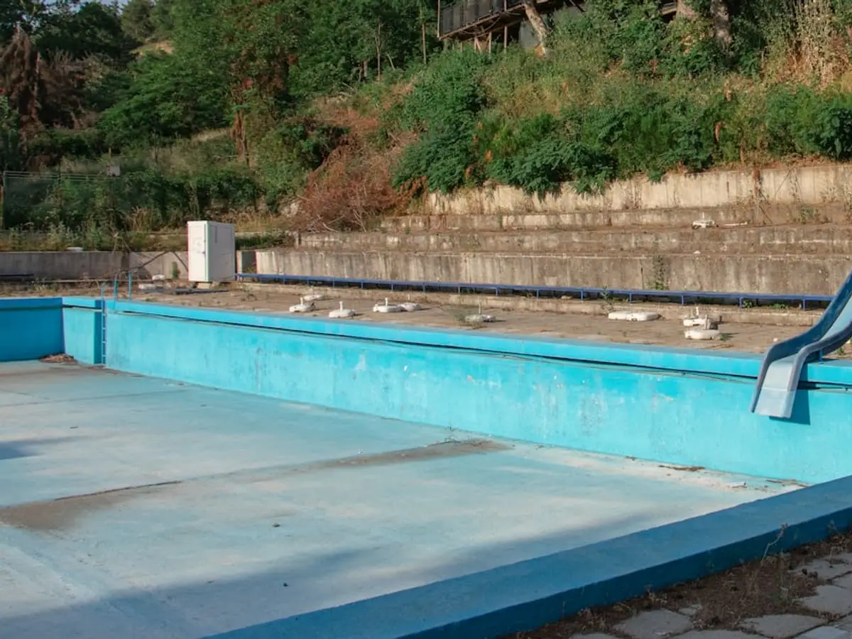 Aging drained in-ground swimming pool awaiting removal